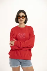 Buzo de algodón rojo con cuello redondo y mangas largas. Estampado frontal con el texto 'Pulau Dept. Since 2023' en color rosa.