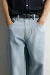 Jeans tapered wide fit de hombre, confeccionados en denim de algodón con efecto lavado en tono azul oscuro. Presentan diseño de cinco bolsillos, tiro medio, corte relajado y cierre frontal con cremallera y botón.