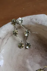 Caravanas colgantes de bronce con diseño de tres discos texturizados unidos por una estructura metálica ondulada.
