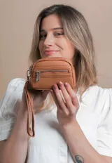 Monedero negro de diseño compacto con textura granulada, cuenta con doble compartimento principal con cierre y un bolsillo frontal adicional con cierre. Incluye una correa de mano extraíble.