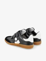 Zapatillas urbanas de cuero blanco con detalles en negro, ajuste con tiras de velcro y suela de goma color caramelo.