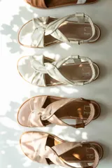 Sandalias chatitas de cuero en tono nude, con diseño de tiras cruzadas en el empeine y elástico en el talón para mayor ajuste. Presentan una plantilla acolchada y detalles en cuero charolado en la parte posterior.