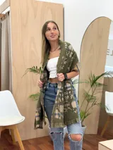 Bufanda rectangular con estampado a cuadros en tonos beige, azul y verde. Tiene flecos en los extremos y un estampado floral en el interior.