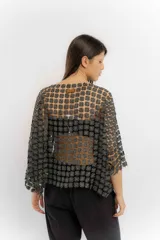 Blusa blanca de encaje con diseño de flores pequeñas entrelazadas, de corte holgado y mangas tres cuartos.