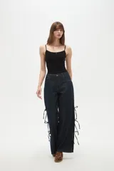 Pantalon de jean azul oscuro de corte ancho y tiro bajo, con detalle de aberturas laterales ajustables mediante lazos.
