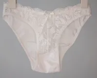 Bombacha de bikini tiro bajo/medio, color negro, confeccionada con tela que contiene fibra LYCRA® y frente de puntilla elastizada.