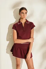 Top de punto color marrón, con cuello polo y cierre frontal parcial, manga corta y detalles de costuras a contratono en los bordes.