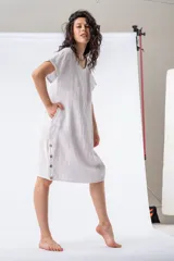 Túnica blanca de lino con cuello en V, mangas cortas y botones decorativos en el lateral.