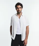 Camisa de manga corta blanca con textura de rayas, cuello inglés y abotonadura frontal.