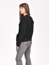 Buzo de tejido de punto negro, con escote en V y diseño cruzado que se ata con un lazo ancho a la cintura. Presenta mangas largas y puños acanalados.