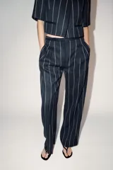 Pantalón de tiro medio de ZARA Woman Collection, confeccionado con mezcla de lino. Presenta diseño de rayas diplomáticas, bolsillos laterales, pinzas en el delantero y cierre frontal con cremallera, botón y ganchos metálicos.