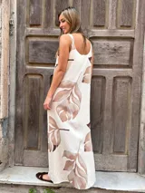Vestido largo con fondo crudo y estampado de hojas marrones, corte recto con escote en V y breteles anchos.