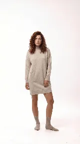 Vestido corto de tejido de punto color beige, con cuello alto, mangas largas y bolsillo frontal aplicado. Presenta un diseño de silueta relajada con terminaciones acanaladas en puños y ruedo.
