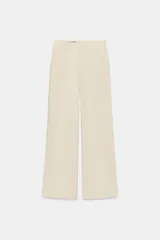 Pantalón de tiro alto con corte fluido y pierna ancha. Presenta pliegues frontales, bolsillos laterales y cierre frontal con cremallera y botón.