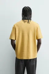 Camiseta de manga corta color crema, con cuello redondo y tejido texturizado con estructura.