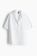 Camisa resort holgada de H&M Divided, color blanco, con mangas al codo, cuello abierto y cierre frontal con botones.