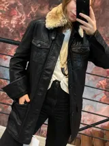 Chaqueta larga de cuero genuino negro, completamente forrada, con cuello desmontable de piel sintética y múltiples bolsillos.
