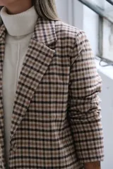 Blazer de corte recto con estampado a cuadros en tonos beige y marrón, con solapas clásicas y cierre frontal.
