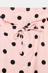 Chaqueta de cuello subido ajustable con lazada, manga larga y cierre frontal con botones. Presenta un diseño estampado de lunares negros sobre fondo rosado, bolsillos laterales y bajo ajustable con cordones.