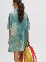 Vestido camisero corto oversize de viscosa con estampado tie-dye en tonos verde agua y blanco, cuello camisero, mangas cortas y bolsillo aplicado en el pecho.