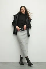 Falda larga gris de punto, ceñida al cuerpo con costuras horizontales.