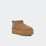Botas de caña baja tipo botineta con plataforma elevada, confeccionadas en gamuza color marrón. Presentan costuras con detalle de puntada overlock, lengüeta trasera y forro interior de lana suave.
