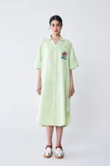 Vestido camisero midi verde claro con botones frontales, mangas cortas, cuello camisero y bolsillo en el pecho con bordado.