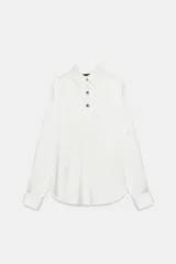 Camisa de satén color blanco, de corte clásico con cuello solapa, manga larga con puños y cierre frontal con botones dorados.