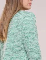 Chaqueta de tweed liviano en color verde, con escote redondo, frente abierto y bolsillos simulados con detalles de pasamanería. Cuenta con mangas largas de corte recto.
