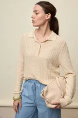 Sweater de punto color beige con relieve geométrico, cuello polo con cartera de tres botones, mangas largas y puños elásticos ribeteados.