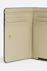 Billetera compacta de cuero vacuno en color negro, con cierre superior metálico dorado y logo de la marca estampado en el frente.