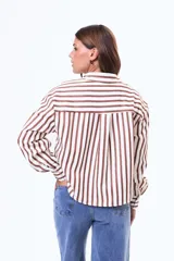 Camisa de manga larga con diseño de rayas verticales en color blanco y negro, cuenta con cuello clásico, cierre frontal de botones y un bolsillo en el pecho.