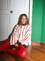 Buzo tejido de punto artesanal, corte oversized, color blanco con rayas verticales bordadas en relieve en color rojo. Presenta cuello redondo y puños en color marrón con destellos de lurex.