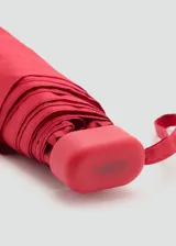 Paraguas mini plegable de color rojo, con tira de sujeción para la muñeca y detalle de placa metálica grabada con el logo de la marca.