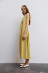 Vestido midi color amarillo con cuello halter, espalda descubierta y lazada en el mismo tejido.