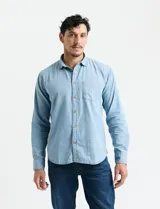 Camisa de denim de algodón con cuello clásico, cierre frontal con botones, bolsillo superior de parche y mangas largas con puños abotonados.