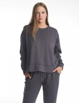 Buzo deportivo de cuello redondo, con hombros caídos y mangas largas con puños. Presenta costuras decorativas tipo pespunte en la parte frontal y en las mangas, con un diseño de ruedo recto y tajos laterales.