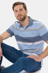 Remera polo de manga corta con cuello y puños en azul oscuro. Presenta un diseño de rayas horizontales en tonos de azul claro, azul oscuro, blanco, amarillo, rosa y verde. Incluye botones personalizados y un logo bordado en el pecho.