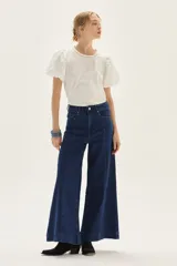 Blusa blanca de calce recto con cuerpo de jersey y mangas cortas tipo globo en popelina. Presenta cuello redondo y detalle de bordado decorativo en la espalda.