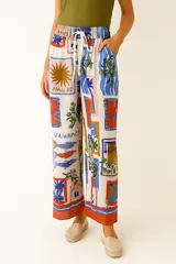 Pantalon de corte ancho y tiro alto, confeccionado en una mezcla de lino y viscosa. Presenta un estampado multicolor con motivos veraniegos y artísticos, cintura elástica con cordón ajustable y bolsillos laterales.