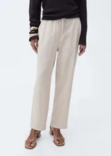 Pantalón fluido de tiro medio, color beige, de corte recto y pernera ancha. Cuenta con cintura elástica con cordón ajustable y bolsillos laterales.