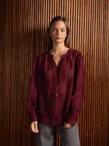 Blusa de tela liviana color crudo, con bordados florales tono sobre tono, escote en V con detalle de puntilla central, mangas largas con volumen y puños camiseros.