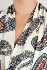 Blusa top fluida sin mangas con cuello halter y estampado paisley en tonos marrones y azules sobre base blanca.