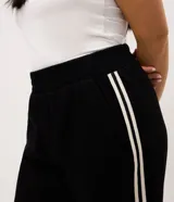 Pantalón pantalona negro de algodón, de corte amplio y cómodo con cintura elástica. Presenta franjas laterales a contratono de diseño deportivo.