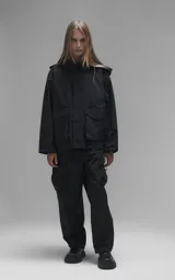 Campera técnica liviana de microfibra negra con acabado mate, capucha ajustable, cierre frontal oculto bajo solapa, bolsillos frontales con solapa y cordón ajustable en la cintura.