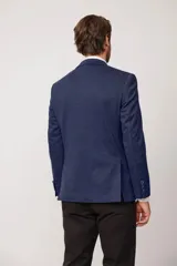 Blazer de corte slim fit en color marrón con textura jaspeada, cierre frontal de dos botones, solapas clásicas y bolsillo en el pecho con pañuelo decorativo.