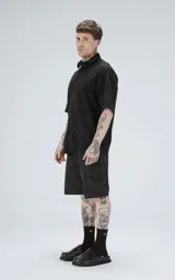 Camisa negra de manga corta con cuello camisero y botones frontales. La tela presenta un patrón texturizado en relieve de motivos florales o abstractos.