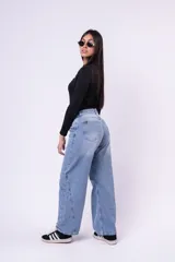 Jean de corte baggy con tiro medio, diseño de pierna ancha y costuras laterales decorativas. Presenta un lavado claro con efecto desgastado.