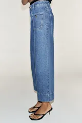 Jeans culotte de tiro alto, color azul, con pernera ancha, nervios marcados en el delantero y bolsillos de parche con botones metálicos. Cuenta con cierre frontal de cremallera y botón metálico.
