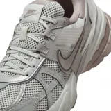 Championes Nike V2K Run de estilo retro-futurista, con diseño en capas de malla y material sintético en tonos beige y gris. Presenta una entresuela robusta con tecnología Cushlon y el logo de Nike en el lateral.
